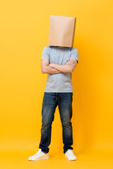Concept full length portrait of Anonymous man with head covered with paper bag doing arms crossed...