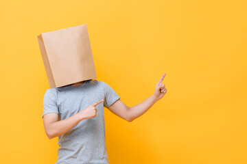 Concept portrait of Anonymous man with head covered with paper bag pointing both fingers up in...