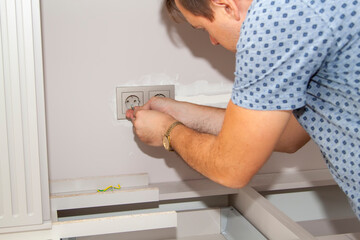 handyman removes the frame from the electrical outlet to fix the problem