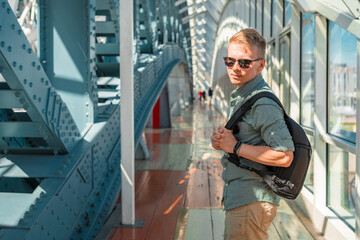 A young man in sunglasses and a shirt walks along a modern glass business corridor