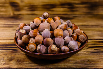 Plate with pile of hazelnuts on a wooden table