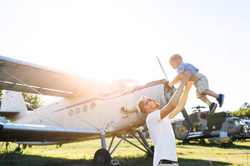 A young father enjoying time with toddler outdoors. A daddy throw son up in the sky, a retro...