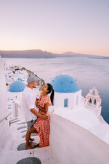 Santorini Greece, young couple on luxury vacation at the Island of Santorini watching sunrise by...