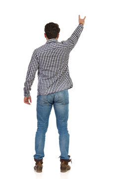Standing Young Man Shows Sign Of The Horns. Rear View.