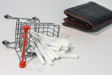 Close up cigarette on mini shopping cart with wallet on white background  with copy specs