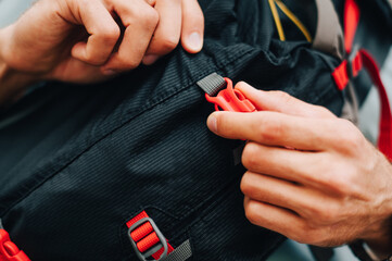 Close photo of a waist bag for tourism, a man's hand holding a fastex. Advertising bags.
