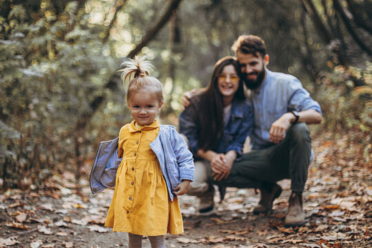 Happy Young Family: Stylish Father, Beautiful Mom And Sweet Little Daughter Spend A Day Together, Child Running In Nature At Sunset. Selective Focus, Noise Effect