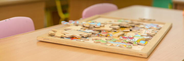 children wood puzzle in box on wooden table in school room