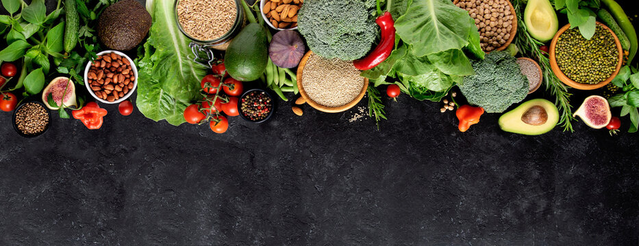 Fresh vegetables, fruits and cereals on a black background, top view, copy space. A balanced vegetarian diet.