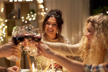holidays, celebration and people concept - happy friends having christmas dinner at home drinking non-alcoholic red wine