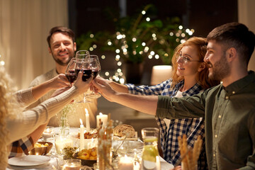 holidays, celebration and people concept - happy friends having christmas dinner party drinking non-alcoholic red wine at home