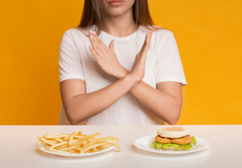 Unrecognizable woman showing stop gesture, refusing unhealthy fast food