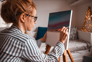 Beautiful artist woman painting in her room.