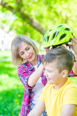 Mother put on helmet to her son for a safe ride on a bike