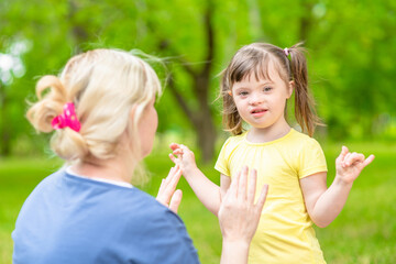 Happy family. Little girl with syndrome down talks with her mother in a summer park