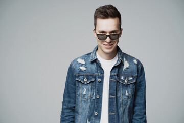 Obraz premium smiling eyes of a young man of European appearance, sunglasses on his face. he looks at his friend. he was wearing a blue denim jacket and a white t-shirt