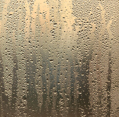 Drops of water on a glass window at dawn as an abstract background.