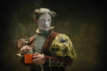 Tea time. Young man as Johann Bach isolated on dark green background. Retro style, comparison of eras concept. Beautiful male model like historical character, great music composer, old-fashioned.