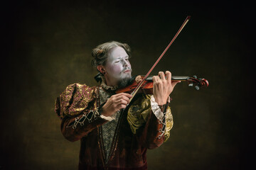 Playing violin. Young man as Johann Bach isolated on dark green background. Retro style, comparison...