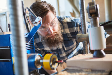 Tischler mit Schutzbrille beim Bohren von Holz