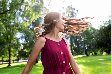 leisure, hairstyle and people concept - portrait of happy smiling beautiful woman with long wavy hair at summer park
