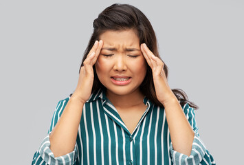 pain, stress and despair concept - stressed asian woman having headache holding to her head over grey background