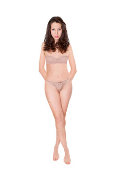 Full length portrait of an attractive woman wearing beige bra and panties, studio photo isolated in front of white background