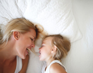 Fototapeta na wymiar portrait of a young woman and her daughter smiling in bed