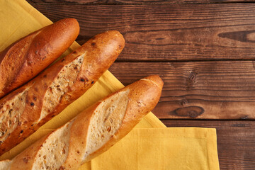 Three crispy french baguettes lie on an old wooden table with free space for text