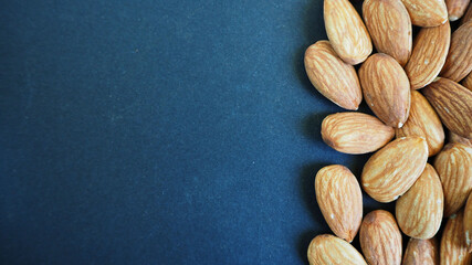 brown almond seeds on the right on a dark blue background top view