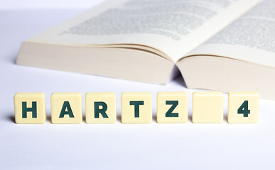 Wort Hartz 4 in Buchstaben mit geöffnetem Buch im Hintergrund