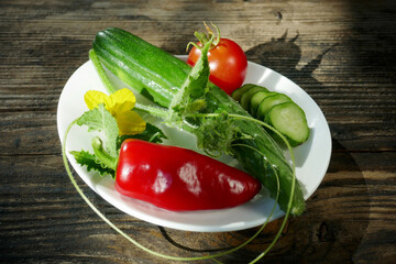 Fresh vegetables in a white plate on a wooden background