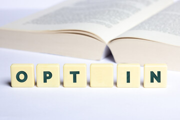 Das Wort "Opt In" mit  aufgeschlagenen Buch im Hintergrund