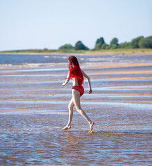 Beautiful redhead young woman in red transparent swimsuit