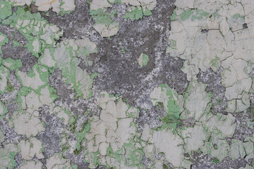 Peeling paint on the wall. Old concrete wall with cracked flaking paint. Weathered rough painted surface with patterns of cracks and peeling. Grunge texture for background and design. High resolution.