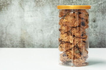 Fresh cookies in plastic jar on white talbe with copy space.