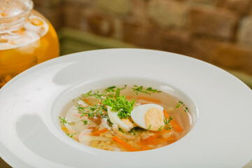 Fresh soup with vegetables, meat and eggs in a white plate.