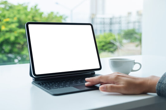 Mockup image of a woman touching on tablet touchpad with blank white desktop screen as computer pc in the office