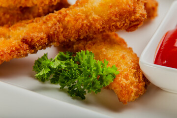 Fresh crispy nuggets with tomato sauce on a white plate.