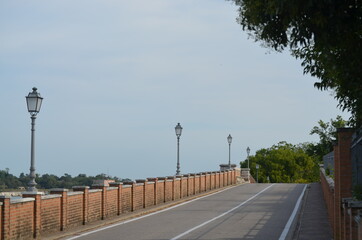 
uphill road bordered by a red brick wall with historic street lamps