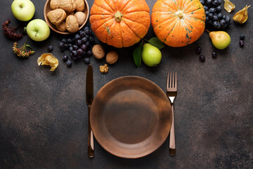 Fall decor for Thanksgiving Day. Bright traditional vegetables and fruits on brown dark background. Pumpkins, grapes, walnuts, apples, pears and leaves. Top view