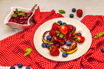 Cottage cheese pancakes with fresh berries and strawberry sauce. Healthy breakfast concept on stone background