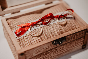 Engagement rings on a wooden box and a red bow.