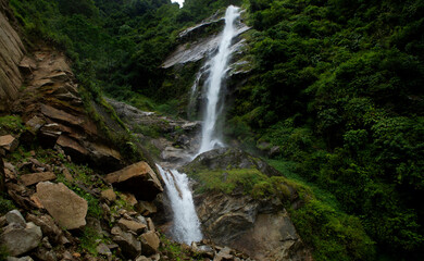 Fototapeta na wymiar A water falls from a high cliff in a rocky forest in Himalaya in Sikkim in India