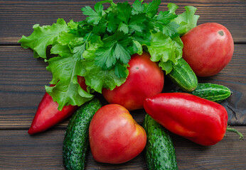 Tomatoes, cucumbers, zucchini, bell peppers, lettuce and parsley on a wooden background close-up.