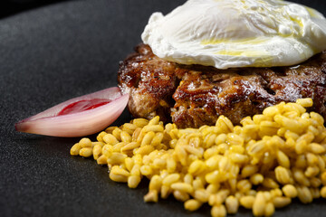 Fried venison steak with poached egg and boiled barley.
