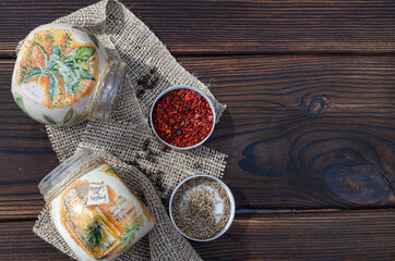 Jars for spices and spices on a rough cloth napkin on a wooden table on the left.