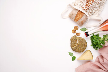 Picnic with rose wine and food. White background with cheese, bread and straw hat. Empty space, food frame