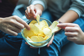 Closeup image of friends sharing and eating potato chips at home party