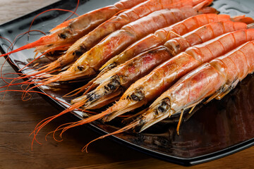 Shrimps on black plate. Tiger shrimps lie in rows.
